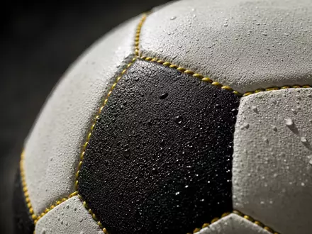 Borussia Dortmund DE0005493092 Makroaufnahme der gelb genähten Lederoberfläche eines professionellen Fußballs mit Wassertropfen - Foto: THN