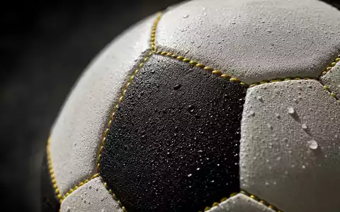 Borussia Dortmund DE0005493092 Makroaufnahme der gelb genähten Lederoberfläche eines professionellen Fußballs mit Wassertropfen - Foto: THN