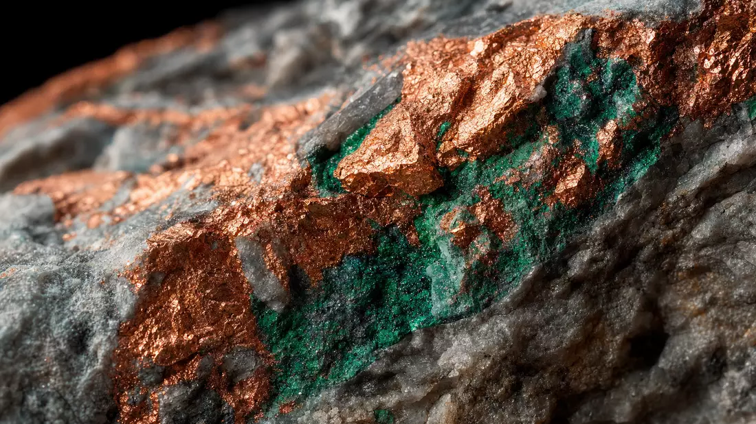 Extreme Nahaufnahme von glänzendem Kupfererz mit grünen Malachit-Mineraladern im Gestein
