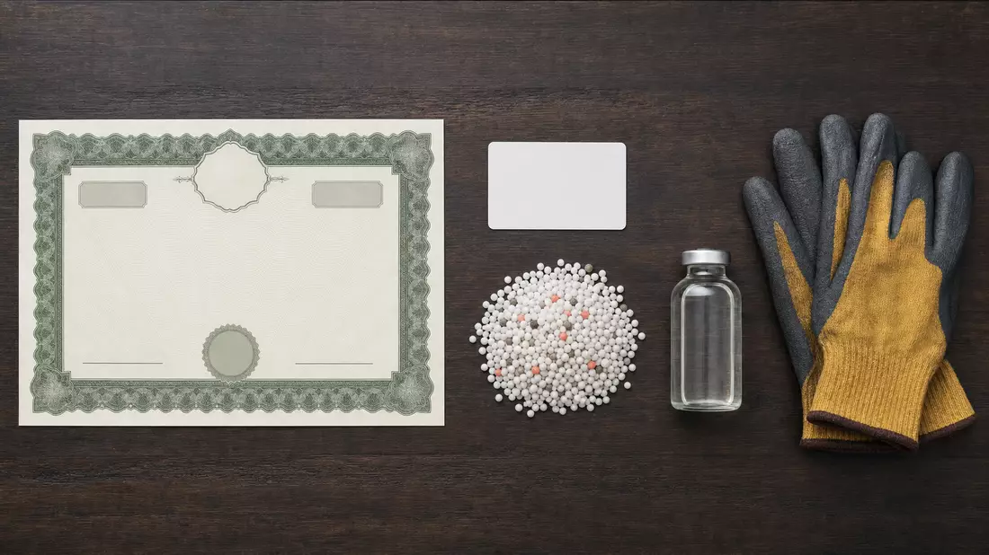 Flatlay mit Aktienzertifikat, ISIN-Karte, Düngerkörnern und Methanolfläschchen