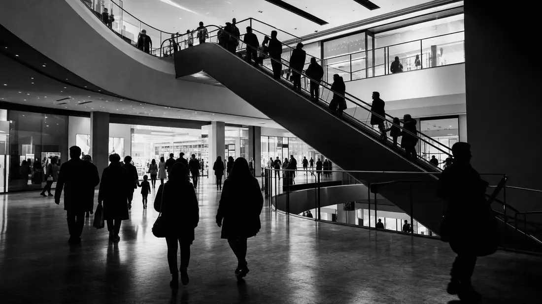 Schwarzweiß-Reportagefoto von Besuchersilhouetten auf Rolltreppen in einem Einkaufszentrum