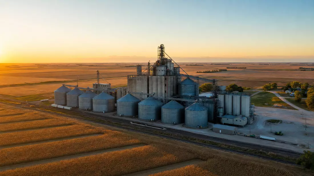 Luftaufnahme eines Getreideelevators mit Silos bei Sonnenuntergang, weite Felder