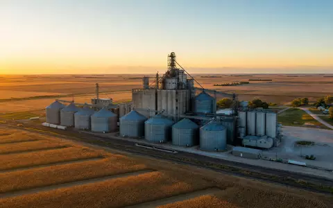 Archer-Daniels-Midland US0394831020 betreibt riesige Getreidesilos inmitten goldener Maisfelder bei warmem Sonnenuntergang in der Midwest-Region - Foto: THN