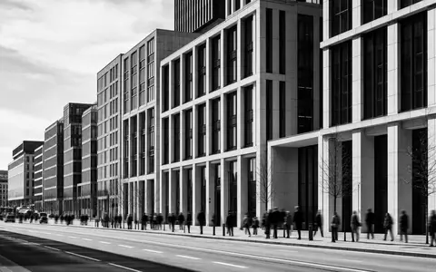 Aroundtown SA LU1673108939 dokumentarische Schwarzweiß-Reportage eines belebten europäischen Büro- und Gewerbeimmobilien-Boulevards mit Passanten - Foto: THN