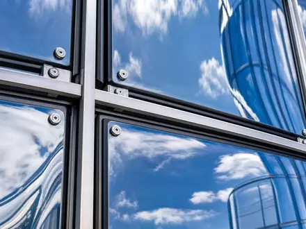 Aroundtown SA LU1673108939 in einer Makro-Detailaufnahme einer blau verspiegelten Glas-Vorhangfassade mit Aluminiumrahmen - Foto: THN