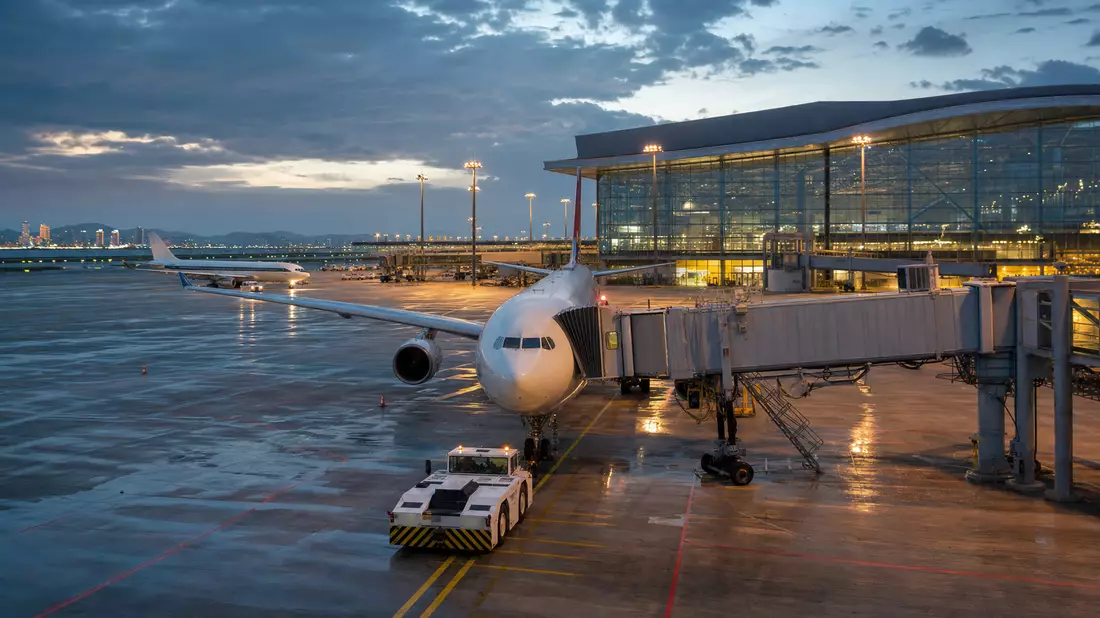 Fotorealistische Nachtszene eines Flughafen-Terminals mit Flugzeug am Gate und Vorfeldbeleuchtung