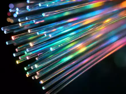 Orange S.A. (FR0000133308) transportiert Daten über Glasfaser, Makroaufnahme zeigt leuchtende bunte Fiberkabel-Enden im Dunkeln - Foto: THN