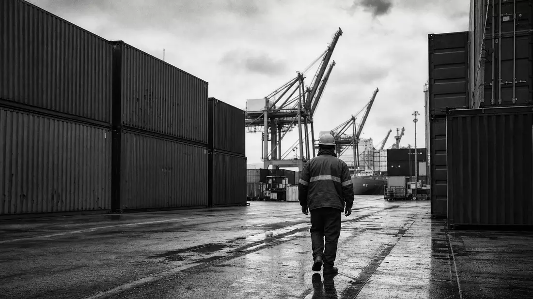 Schwarzweißfoto: Hafenarbeiter zwischen Containern am Kran, DSV A/S DK0060079531