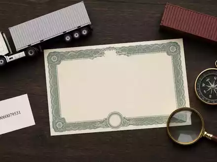 DSV A/S (ISIN DK0060079531) illustriert als Flatlay mit Aktienzertifikat, ISIN-Karte, Miniatur-LKW und Container-Modell - Foto: THN