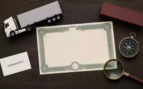 DSV A/S (ISIN DK0060079531) illustriert als Flatlay mit Aktienzertifikat, ISIN-Karte, Miniatur-LKW und Container-Modell - Foto: THN