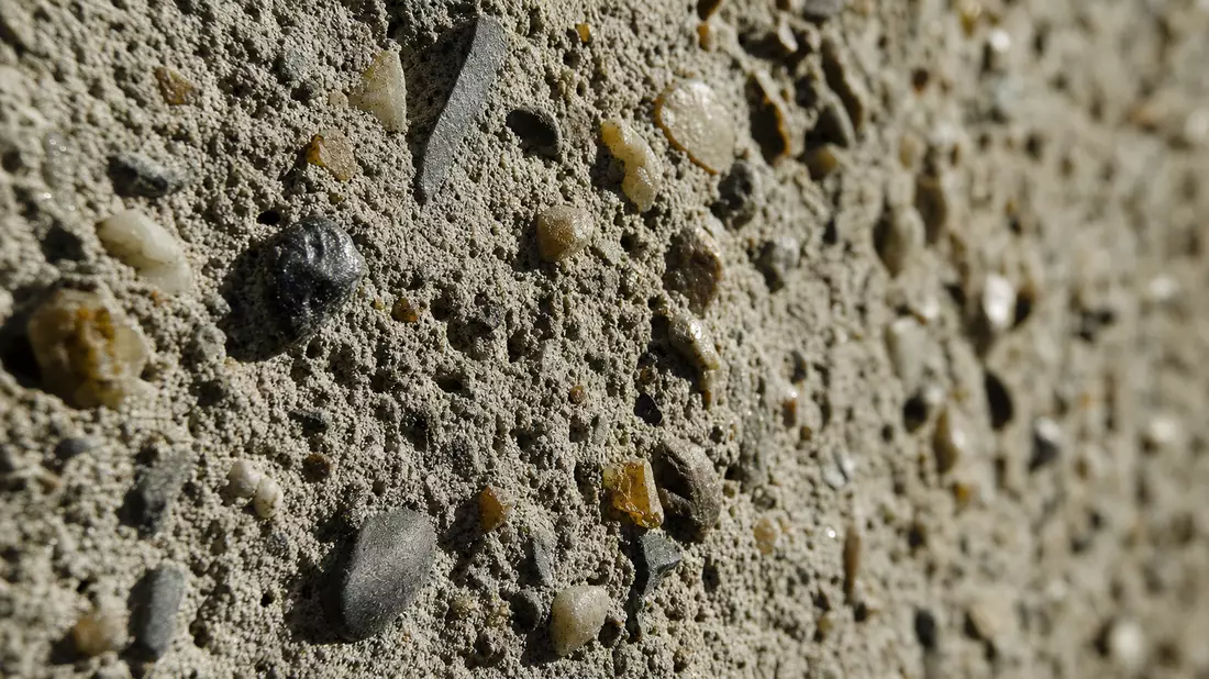 Makroaufnahme einer körnigen Betonoberfläche mit sichtbarem Kies und Sand