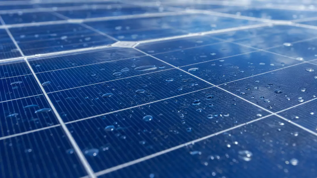 Makroaufnahme einer Solarzelle mit Tautropfen und blauer Spiegelung
