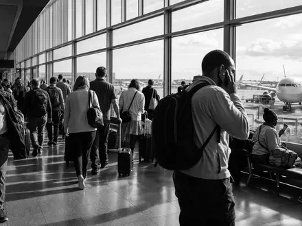 International Consolidated Airlines Group S.A. (ES0177542018): dokumentarische Schwarzweiß-Reportage zeigt Reisende im belebten Flughafenterminal - Foto: THN