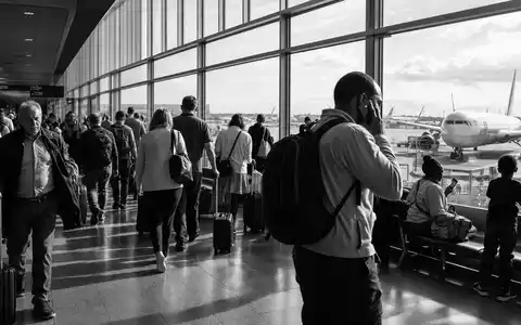 International Consolidated Airlines Group S.A. (ES0177542018): dokumentarische Schwarzweiß-Reportage zeigt Reisende im belebten Flughafenterminal - Foto: THN