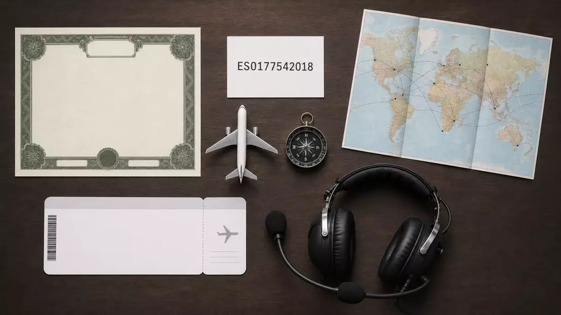 Flatlay mit Aktienzertifikat, ISIN-Karte, Flugzeugmodell und Kopfhörern