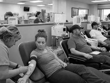 Dokumentarische Schwarzweiß-Reportage porträtiert Grifols S.A. ES0171996087 im Alltag einer Plasma-Spendeklinik mit medizinischem Personal - Foto: THN