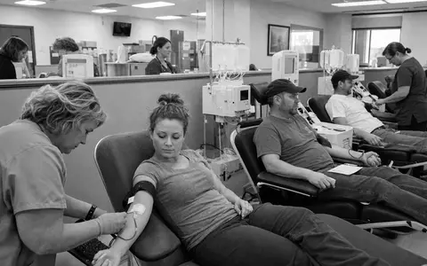Dokumentarische Schwarzweiß-Reportage porträtiert Grifols S.A. ES0171996087 im Alltag einer Plasma-Spendeklinik mit medizinischem Personal - Foto: THN