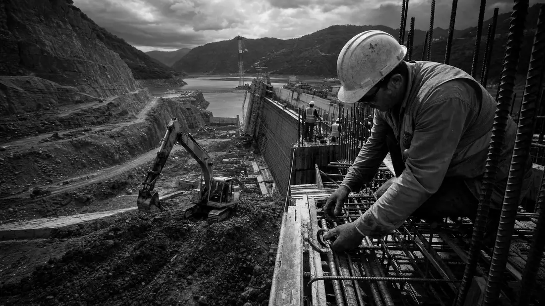 Schwarzweiß-Dokumentarfoto von Bauarbeitern und schwerem Baugerät auf Großbaustelle