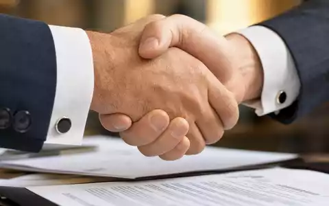 Makroaufnahme eines Geschäftshändedrucks veranschaulicht Adecco Group AG, ISIN CH0012138530, als führenden Anbieter für Personalvermittlung - Foto: THN