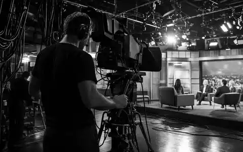 ITV plc GB0033986497 schwarzweiße Reportage zeigt Kameramann bei Live-Übertragung mit dramatischer Hochkontrast-Dokumentarfotografie im Studio - Foto: THN