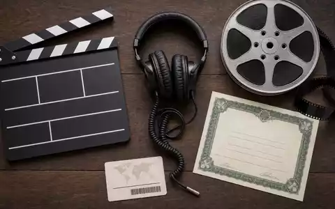 ITV plc GB0033986497 Flatlay generisches Klappboard Kopfhörer Filmrolle Aktien-Zertifikat ISIN-Karte Holztisch Anordnung - Foto: THN