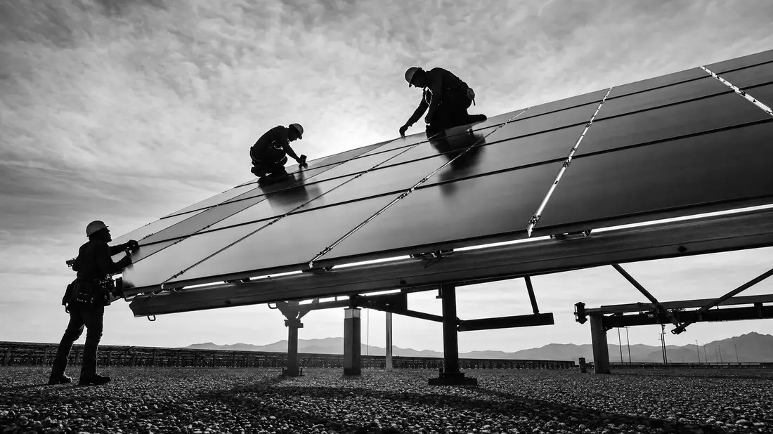 Schwarzweiß-Reportage: Arbeiter installieren Solarmodule bei First Solar Inc., ISIN US3364331070