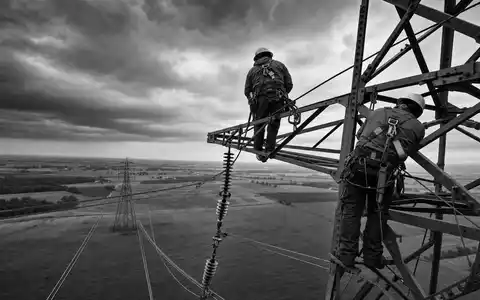 FirstEnergy Corp. zeigt Leitungsmonteure hoch auf einem Stahlmast im Reportage Stil ISIN US3377381088 - Foto: THN