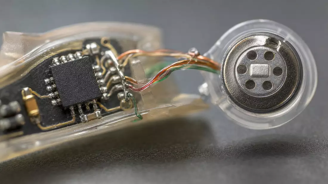 Makroaufnahme eines Hörgerät-Mikrochips mit Drähten und Miniaturlautsprecher