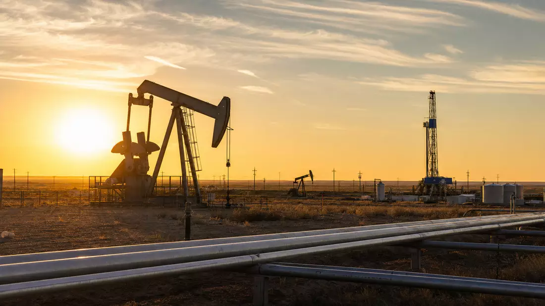 Ölfeld mit Pumpjacks und Bohrturm bei Sonnenuntergang, symbolisch für Marathon Oil