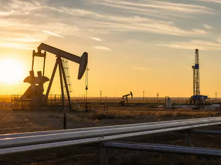 Marathon Oil (US5658491064): fotorealistisches Ölfeld bei Sonnenuntergang zeigt Pumpjacks, Bohrturm und Pipelines in weiter Wüstenlandschaft - Foto: THN