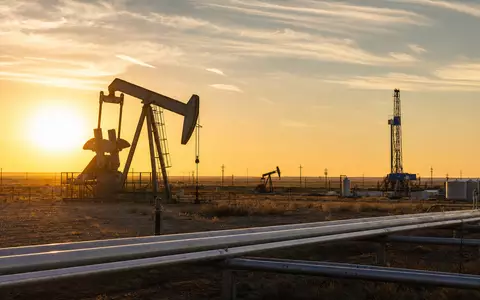 Marathon Oil (US5658491064): fotorealistisches Ölfeld bei Sonnenuntergang zeigt Pumpjacks, Bohrturm und Pipelines in weiter Wüstenlandschaft - Foto: THN