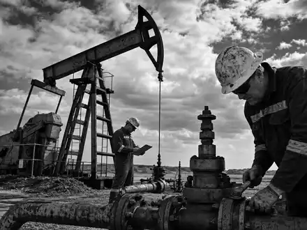 Marathon Oil (US5658491064): dokumentarische Schwarzweiß-Reportage zeigt Ölarbeiter bei Wartung einer Pumpjack-Anlage im Feld - Foto: THN