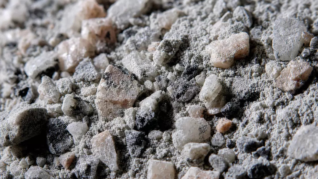 Makroaufnahme von zerkleinertem Granit und Zementpulver mit Lichtkontrast