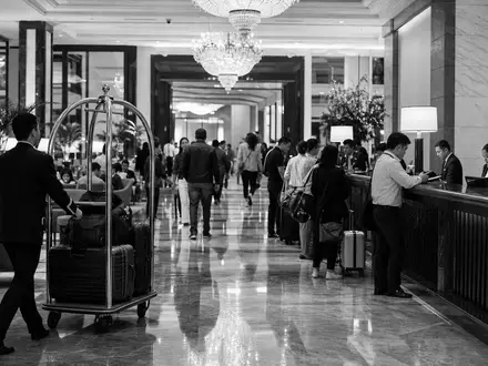 Marriott International US5719032022 wird durch dokumentarische Schwarzweiß-Reportage einer belebten Hotellobby mit Gästen dargestellt - Foto: THN