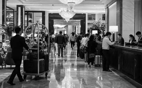 Marriott International US5719032022 wird durch dokumentarische Schwarzweiß-Reportage einer belebten Hotellobby mit Gästen dargestellt - Foto: THN