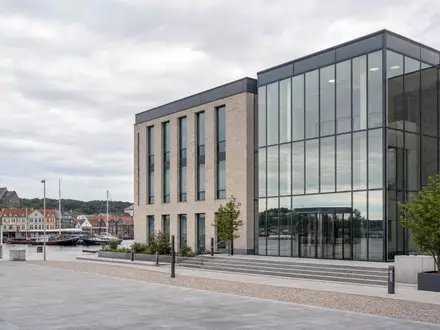 Fotorealistisches Bankgebäude in Aabenraa zeigt Sydbank A/S, dänische Bank mit ISIN DK0010311471 am Wasser - Foto: THN