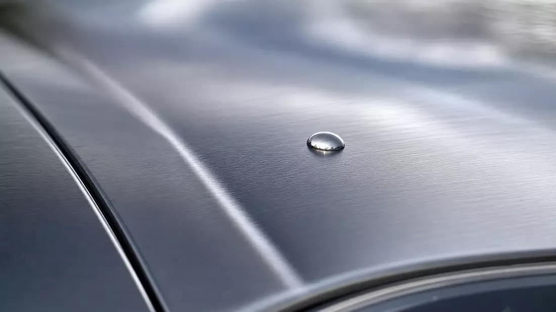 Makrofoto eines Wassertropfens auf gebürsteter Aluminiumoberfläche