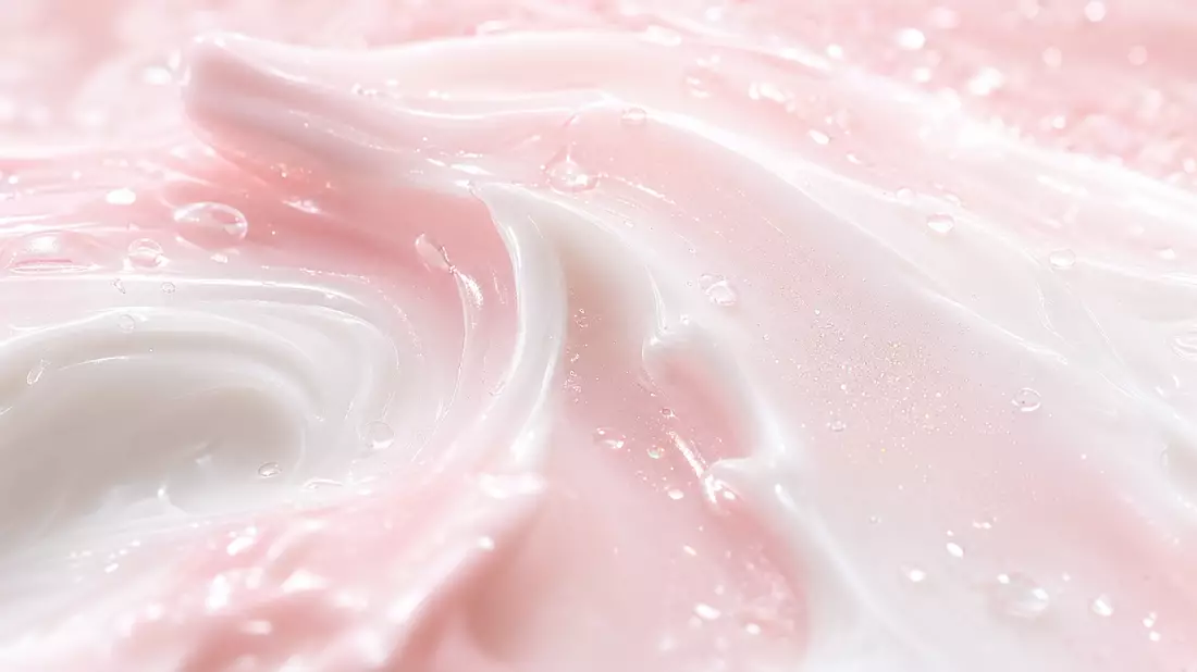 Makroaufnahme einer cremigen rosa-weißen Hautpflegelotion mit Wassertropfen