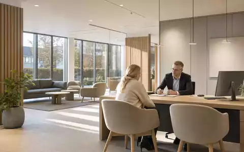 Jyske Bank A/S (DK0010307958) zeigt eine moderne Filiale mit Beratungsgespräch am Tisch im skandinavischen Stil - Foto: THN