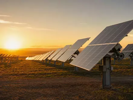 AES Corp. US00130H1059 utility-scale solar farm with sun-tracking panels at golden sunrise - Foto: THN