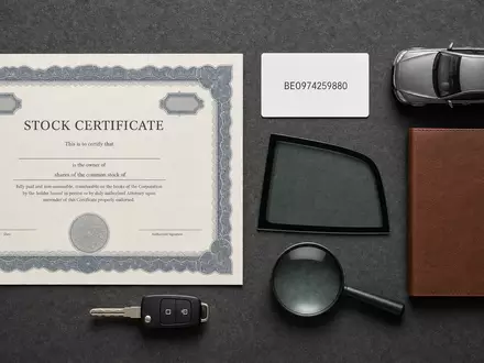 D'Ieteren Group BE0974259880 arrangiert Flatlay mit Aktienzertifikat, ISIN-Karte, Modellauto, Glasscheibe und blankem Notizbuch - Foto: THN