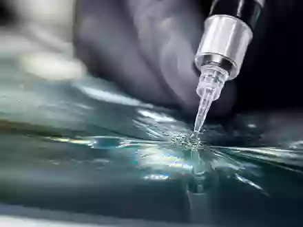 D'Ieteren Group BE0974259880 zeigt Makroaufnahme einer Windschutzscheibenreparatur mit Harzinjektion und Lichtreflexionen im Glas - Foto: THN