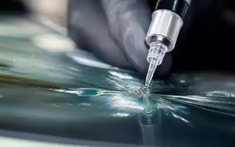 D'Ieteren Group BE0974259880 zeigt Makroaufnahme einer Windschutzscheibenreparatur mit Harzinjektion und Lichtreflexionen im Glas - Foto: THN