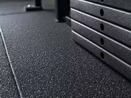 Makroaufnahme von Gummiboden und Gewichtsplatten zeigt Materialien der Fitnessbranche von Technogym S.p.A., ISIN IT0005162406 - Foto: THN