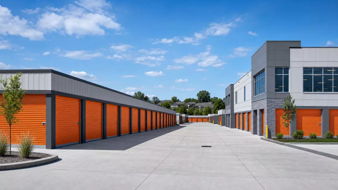 Modernes Self-Storage-Gelände mit orangefarbenen Rolltoren und Betoneinfahrt bei blauem Himmel