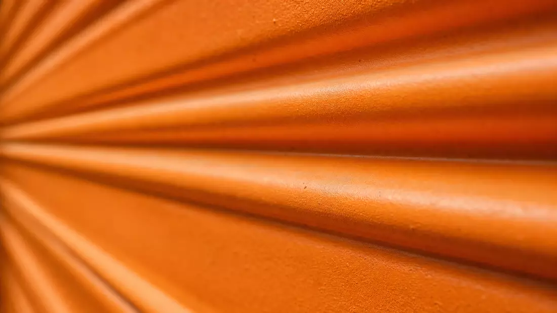 Extreme Nahaufnahme der orangefarbenen Wellblechtextur eines Lager-Rolltors im Querformat