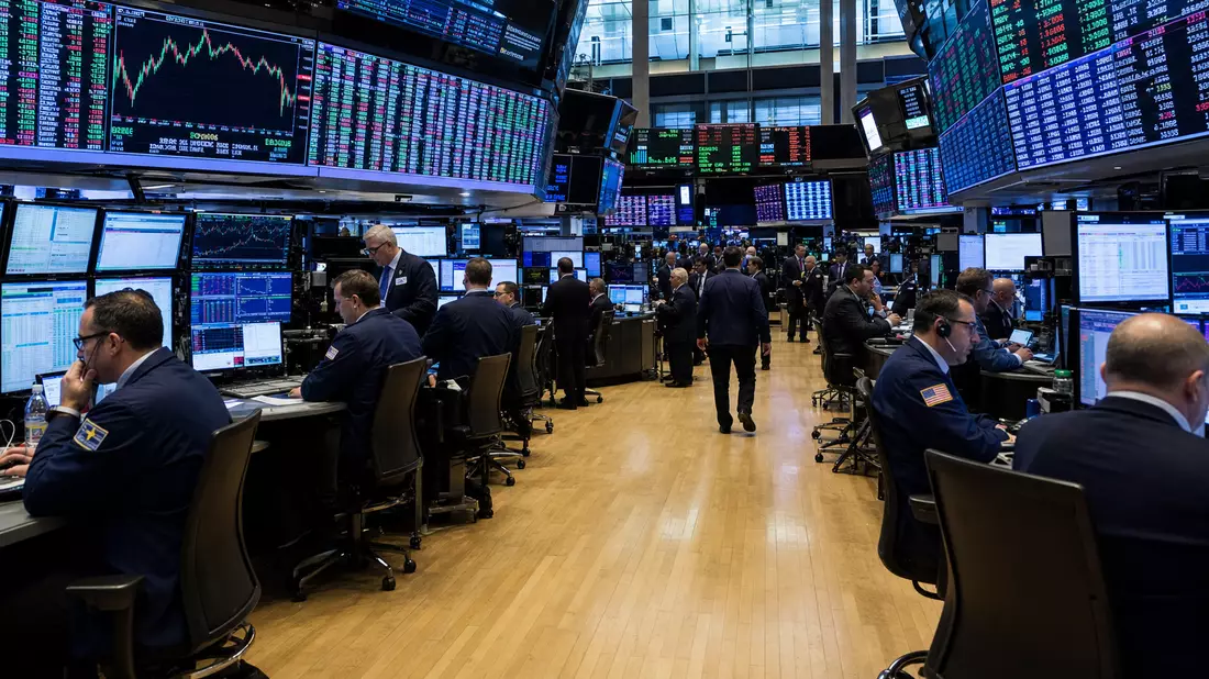 Trading-Floor mit Händlern an Computern, große Anzeigetafeln mit Börsenkursen und Finanzdaten