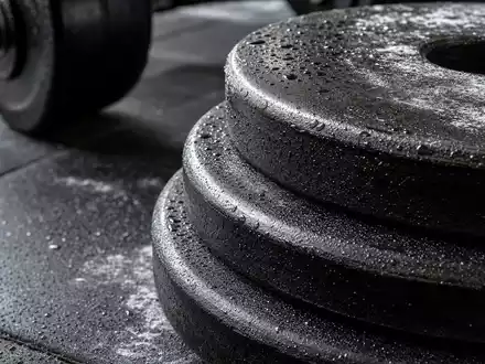 Makroaufnahme von Hantelscheiben und Gummiboden zeigt Detailmaterial der Fitnessbranche von Basic-Fit N.V., ISIN NL0011872650 - Foto: THN