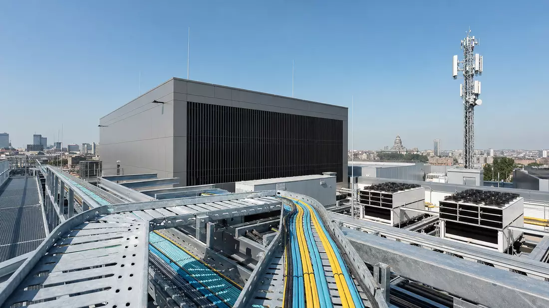 Fotorealistisches Rechenzentrum mit Glasfaserkabeln und Sendemast über Brüsseler Skyline