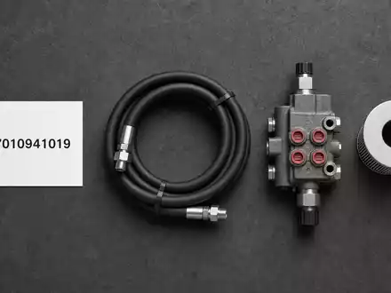 Parker-Hannifin US7010941019 Flatlay mit ISIN-Karte, Hydraulikschlauch, Ventil und Filterelement auf grauem Untergrund - Foto: THN